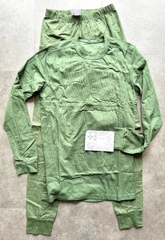 Green long-sleeve shirt and pants laid flat on a gray surface