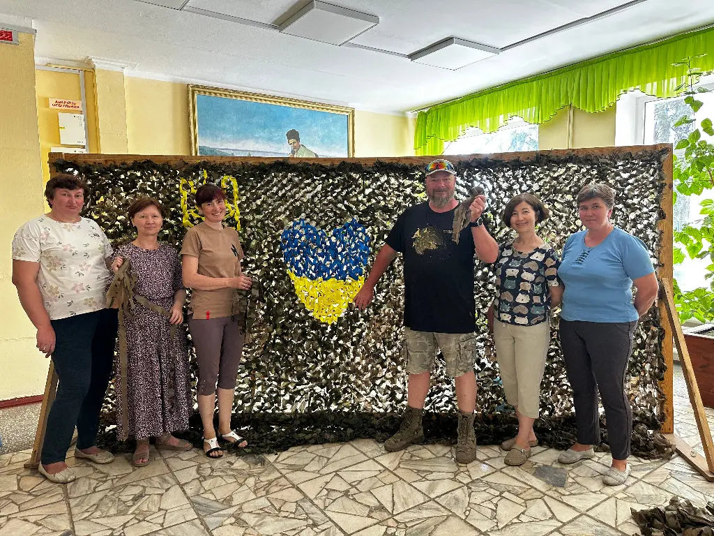 Group of people posing in front of a decorative wall with a blue and yellow heart design, likely representing Ukraine.