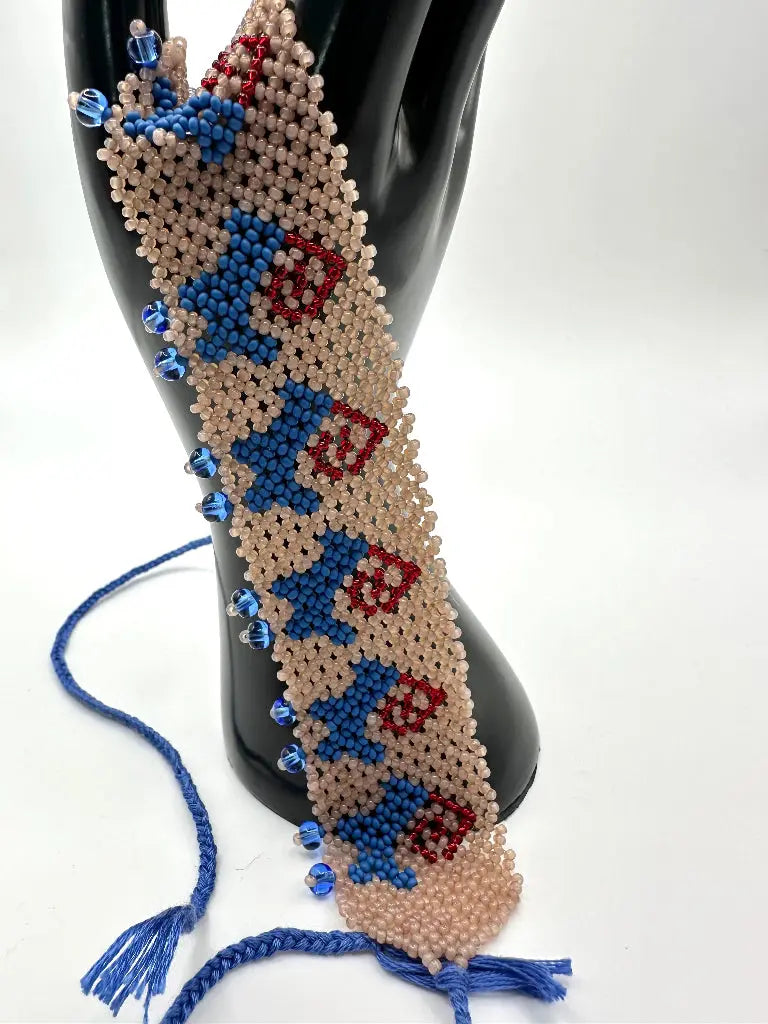 Beaded bracelet with blue and red patterns on a black mannequin arm against a white background