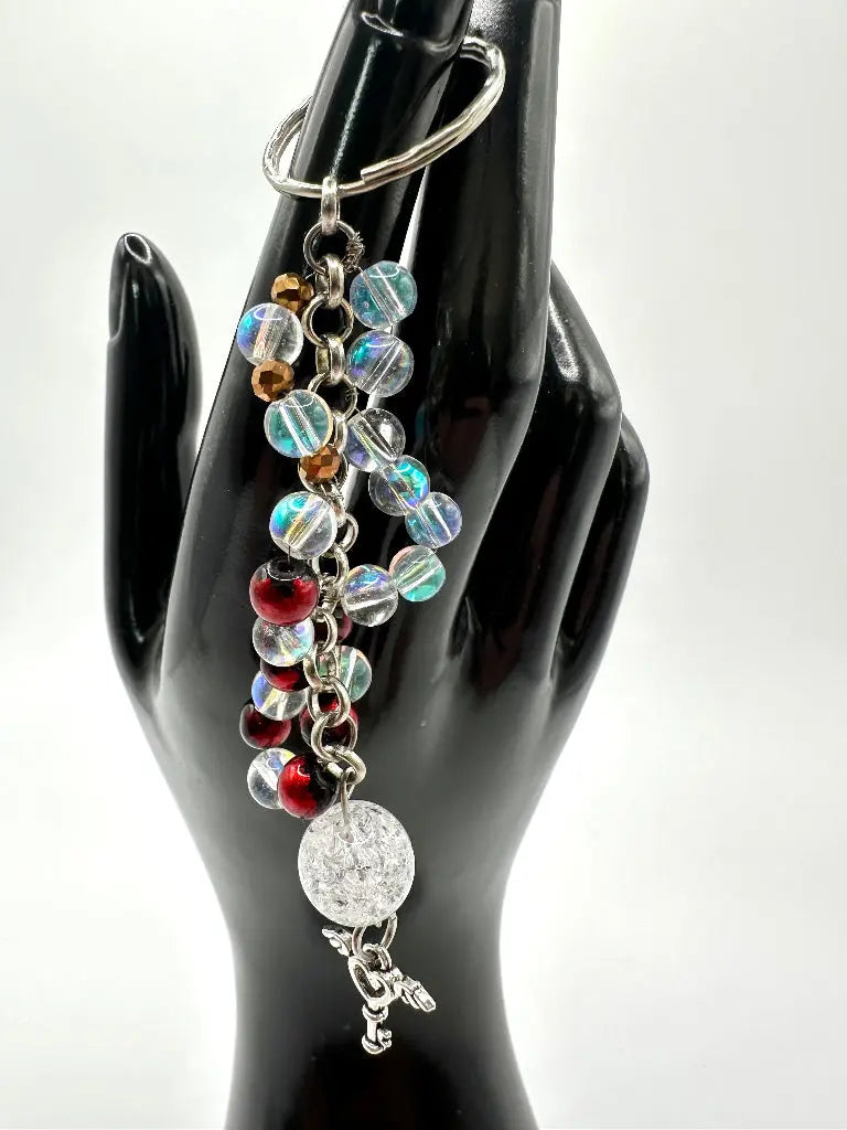 Multicolored beaded keychain on a black mannequin hand against a white background