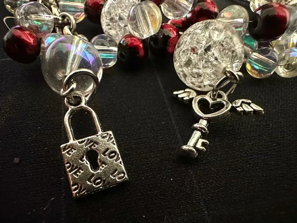 Bracelet with lock charm and heart angel wing charm on a dark background