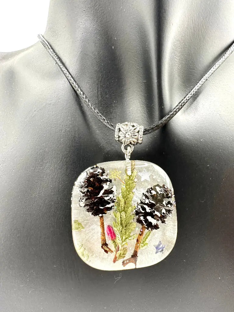 Square pendant with nature-themed design on a mannequin bust.