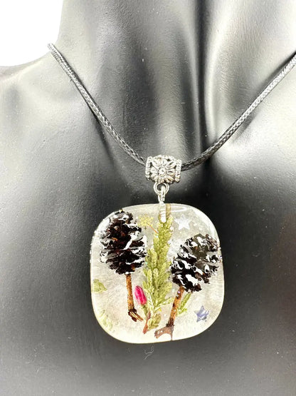 Square pendant with nature-themed design on a mannequin bust.
